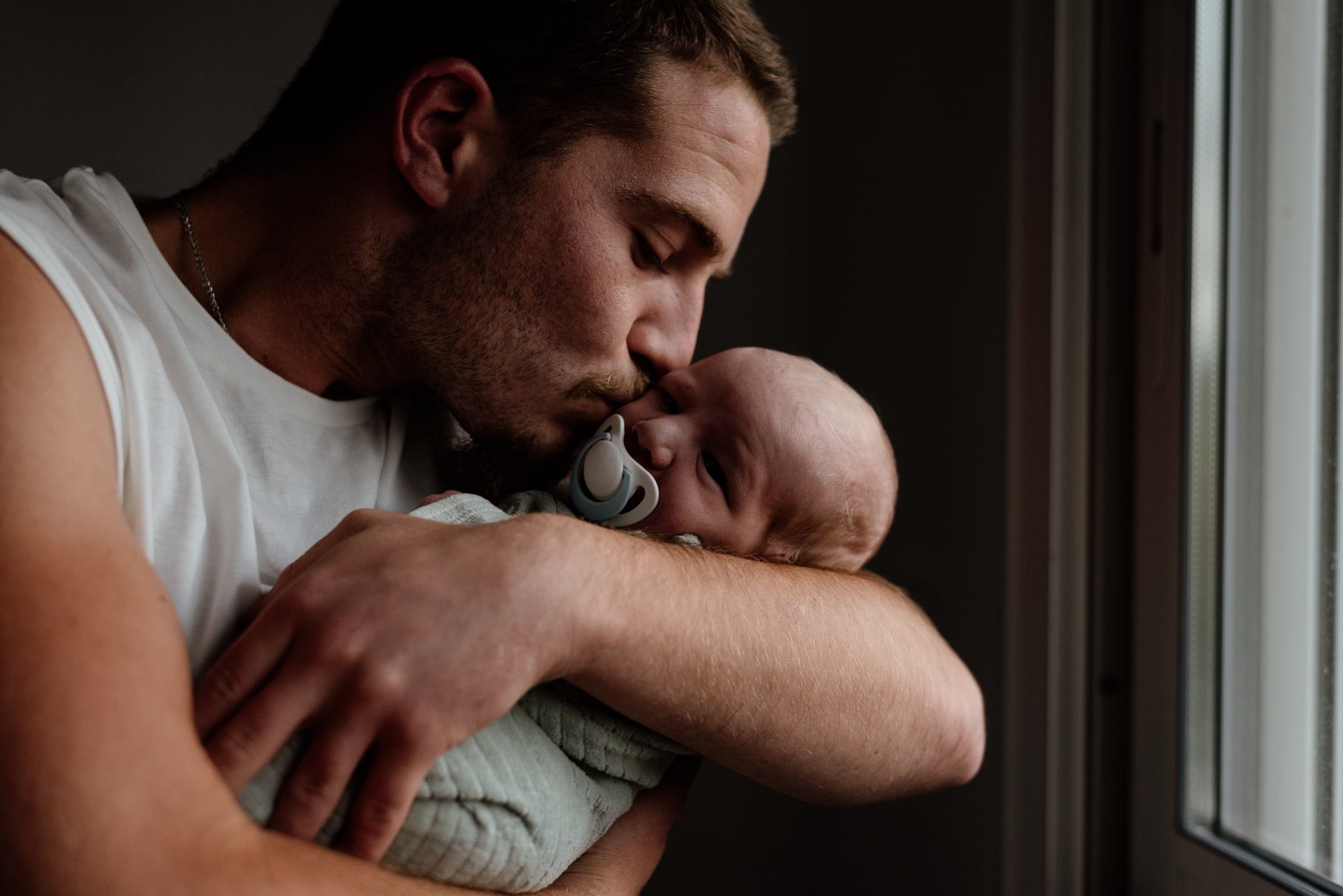 Un papa embrassant son nouveau-né sur la joue en maternité